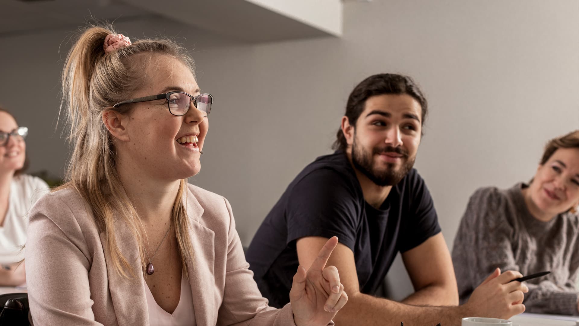 Kvinna och man sitter vid ett bord med papper och pennor framför sig. De tittar förbi kameran och ler.