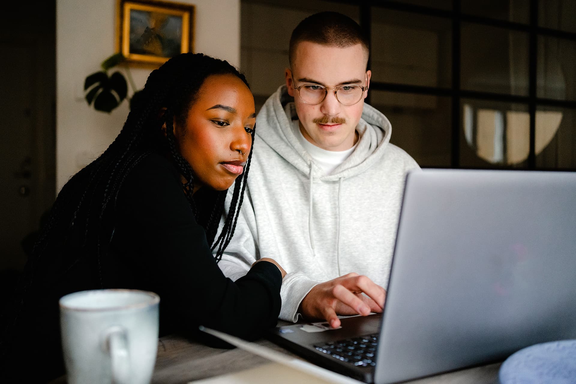 Två ungdomar vid ett skrivbord som kollar i en laptop