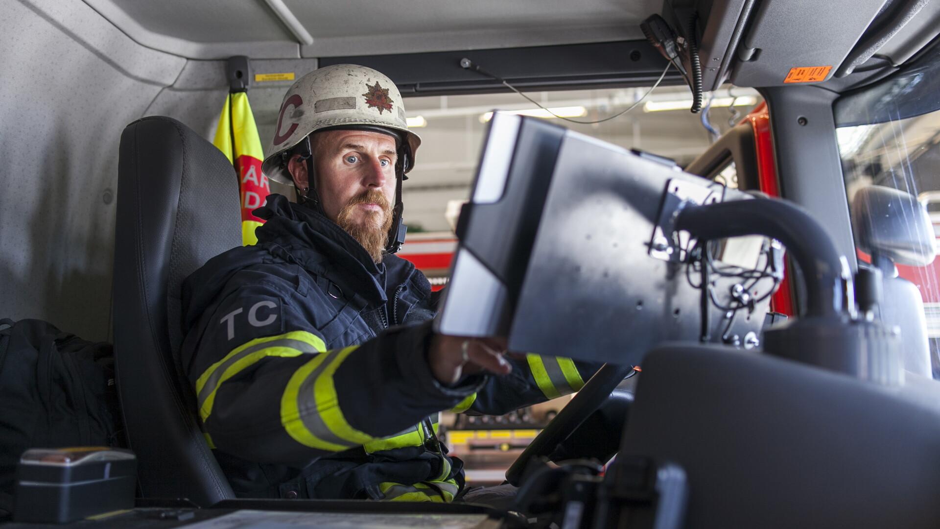 Brandman pekar på datorskärm i förarhytten i brandbil.